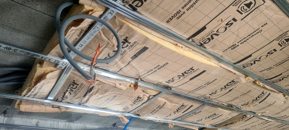 2026.01.12 - Pose de l'isolant au dessus des fourrures du faux-plafond dans la partie nord de la grande pièce